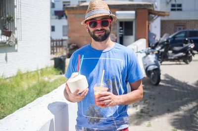 Smiling man holding coconut water on walkway