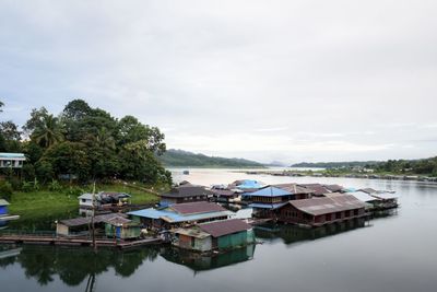 Houses by lake and buildings against sky