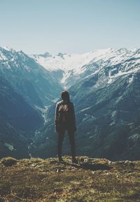 Rear view of man standing on mountain against sky