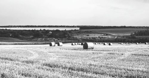 Scenic view of hay bales on field against clear sky