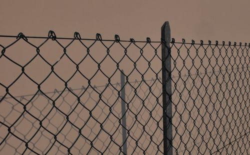 Close-up of chainlink fence against during foggy weather