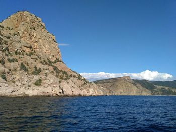 Scenic view of sea and mountains against blue sky