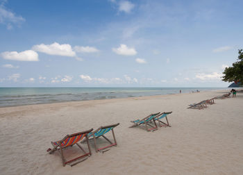 Deck chairs on beach against sky