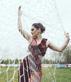 Beautiful young woman posing by net on playing field