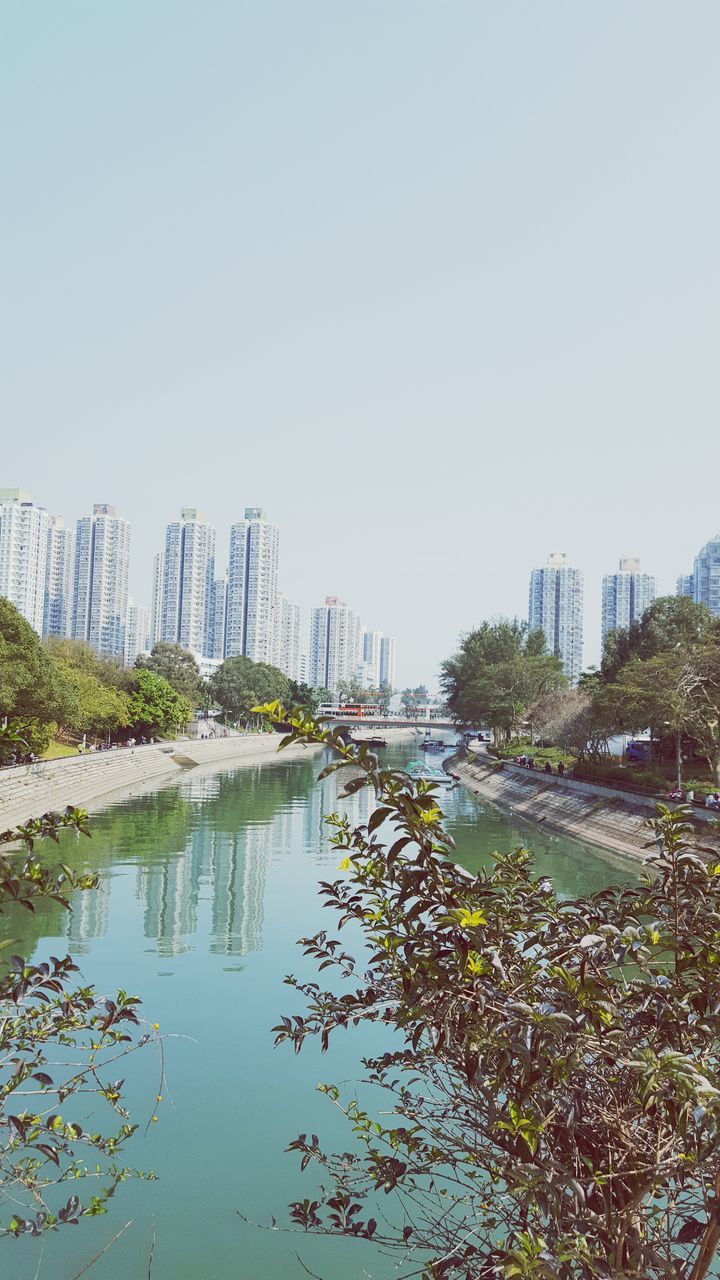 copy space, reflection, water, architecture, clear sky, building exterior, city, built structure, tree, growth, day, nature, no people, outdoors, waterfront, skyscraper, cityscape, urban skyline, beauty in nature, sky