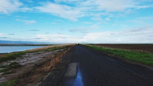 Empty road amidst land against sky