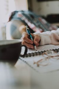 Cropped hand writing in book on table