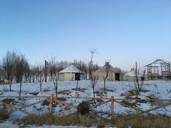 Houses on snow covered field against sky