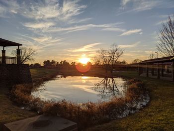 Scenic view of canal by buildings against sky during sunset