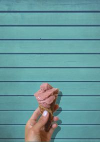 Cropped hand holding ice cream cone on wood