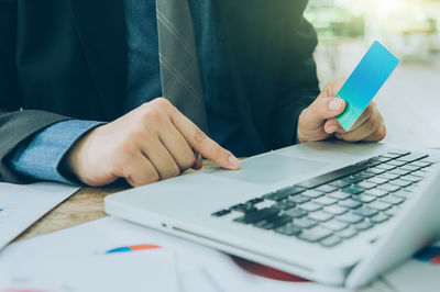 Midsection of man using mobile phone on table