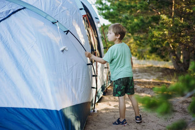 Cute little caucasian boy helping to put up a tent. family camping concept