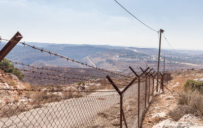 Barbed wire fence on landscape against sky