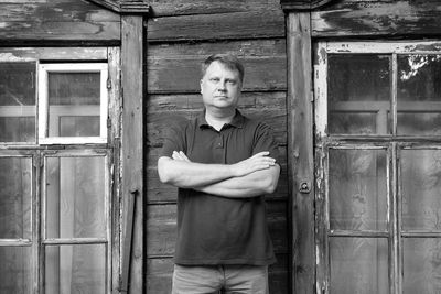 Portrait of young man standing against door