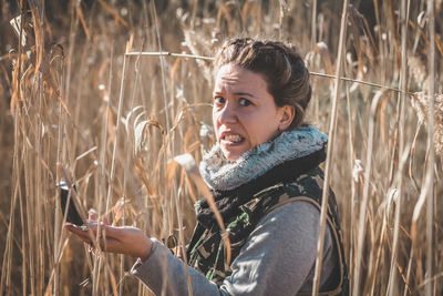 Woman holding mirror compass standing amidst field in forest