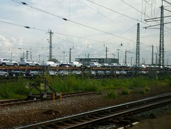 Cars parked on railroad tracks in town against sky