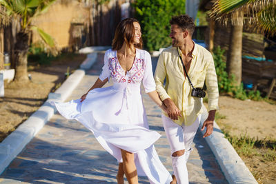 Smiling couple holding hands walking on footpath