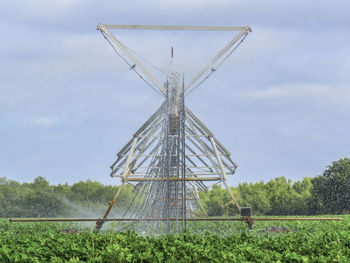 Irrigation equipment on landscape against sky during sunny day