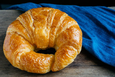 Close-up of croissant by blue fabric on table