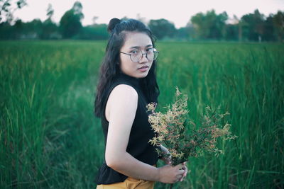 Beautiful young woman wearing sunglasses standing on field