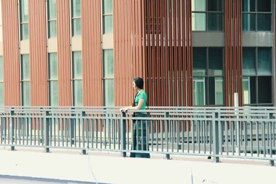 Woman standing on bridge against building