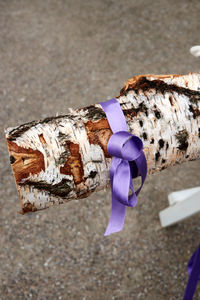 Close-up of hand holding wood with ribbon