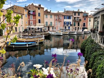 Sailboats moored on canal by buildings in city