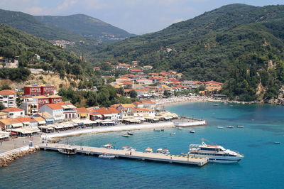 Scenic view of town by sea against forest mountain