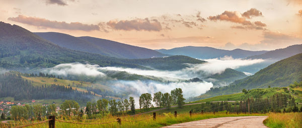 Panoramic shot of road amidst field against sky