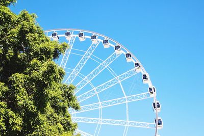 Low angle view of ferris wheel against clear blue sky