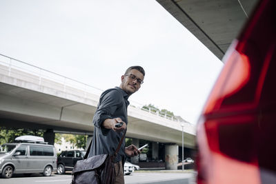 Young businessman using remote control key of car