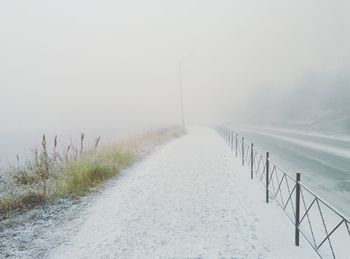 Empty road along snow covered landscape