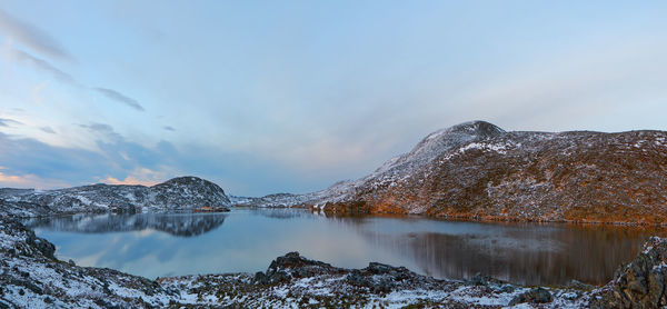 Scenic view of lake by snowcapped mountain against sky