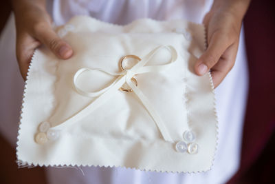 Midsection of bride holding wedding rings on pillow