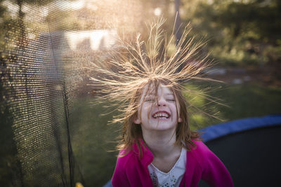 High angle view of cheerful girl jumping on trampoline in backyard