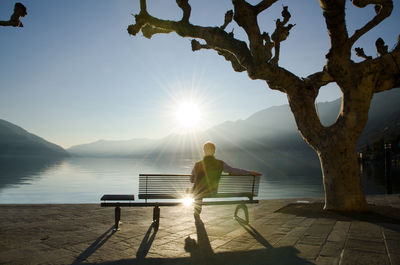 People sitting on bench at sunset