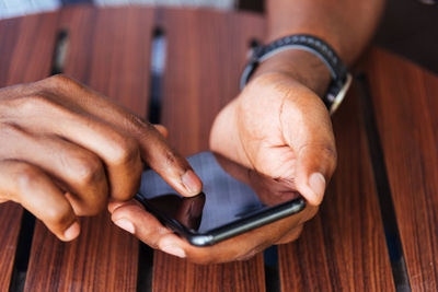 Close-up of man using mobile phone on table