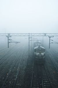 Railroad tracks in foggy weather against sky during winter