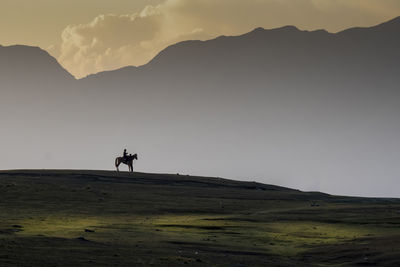 People riding on mountain against sky