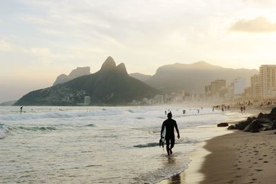 View of silhouette man on ipanema beach against golden sky