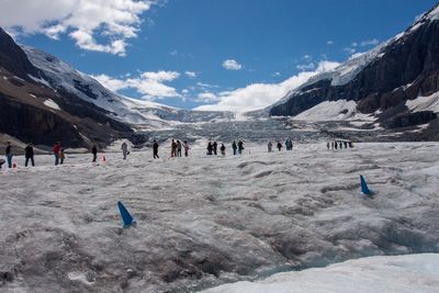 Group of people on snowcapped mountain against sky