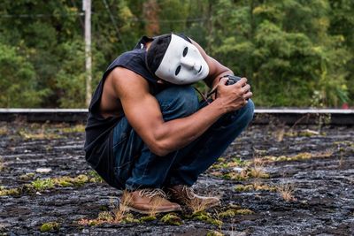 Full length of man crouching while photographing on footpath