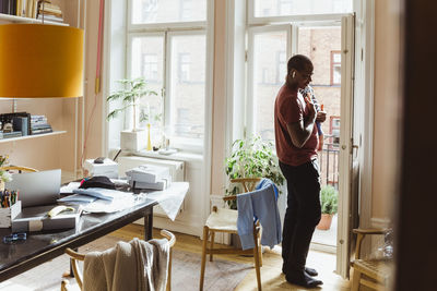 Businessman carrying baby boy while standing by door at home office