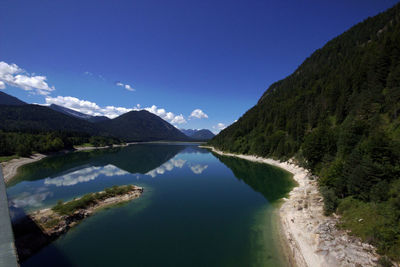 Scenic view of lake and mountains against blue sky