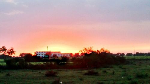 Scenic view of grassy field against sky at sunset