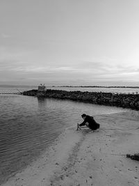 Rear view of woman walking on beach against sky