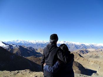 Rear view of people looking at mountain against sky