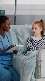 Female friends using digital tablet while sitting on bed at home