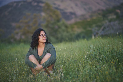 Portrait of a young woman sitting in a meadow at sunset. the sun illuminates her face.