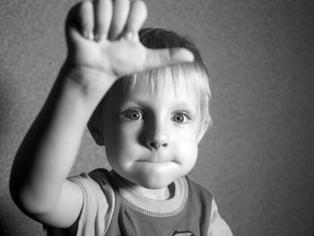 Portrait of cute boy gesturing against wall